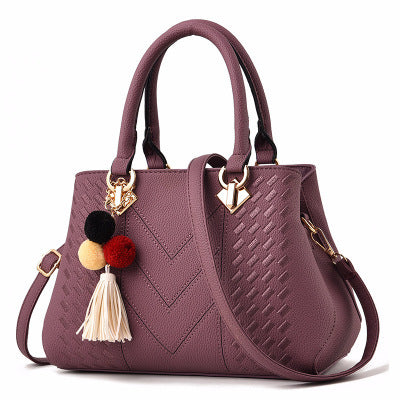 Beautiful purple luxury handbag for women, showcasing a sleek design and vibrant pom-pom charm.