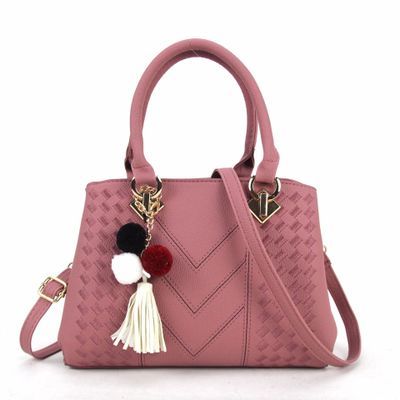 Soft pink luxury handbag for women with a fashionable look, enhanced by decorative tassels and gold details.