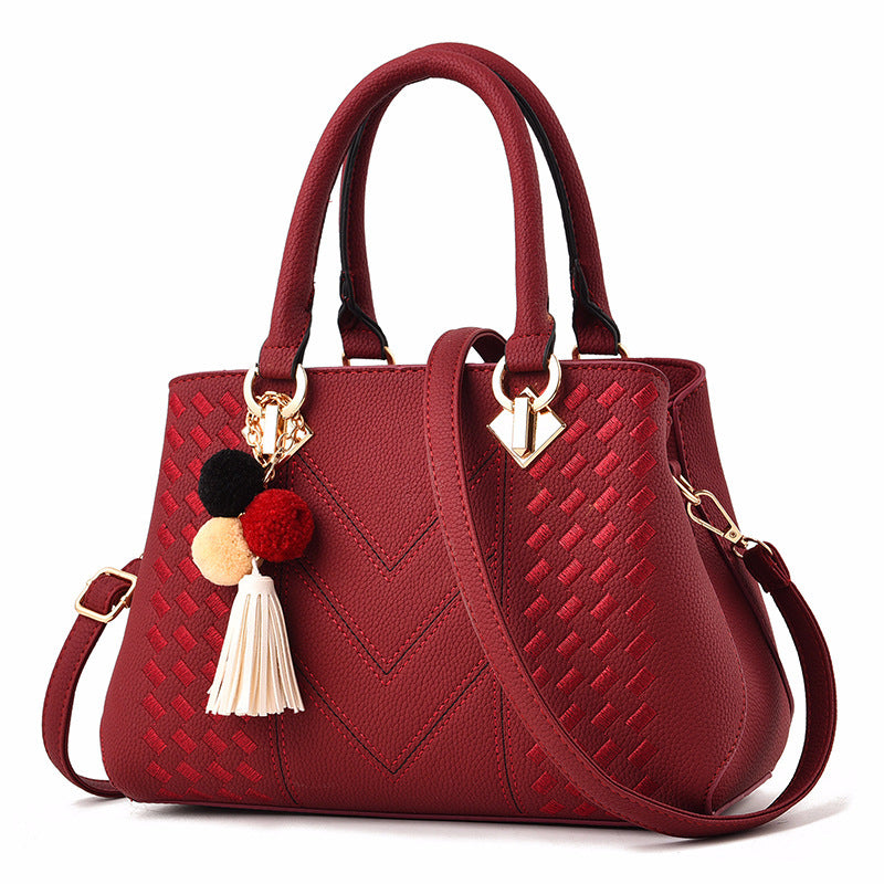 Stunning red luxury handbag for women, featuring a chic design with cute pom-pom accents and gold hardware.