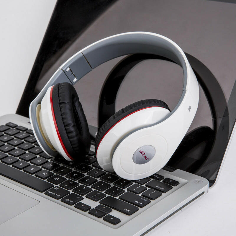 White wired gaming headphones resting on a laptop keyboard with black and red accents.