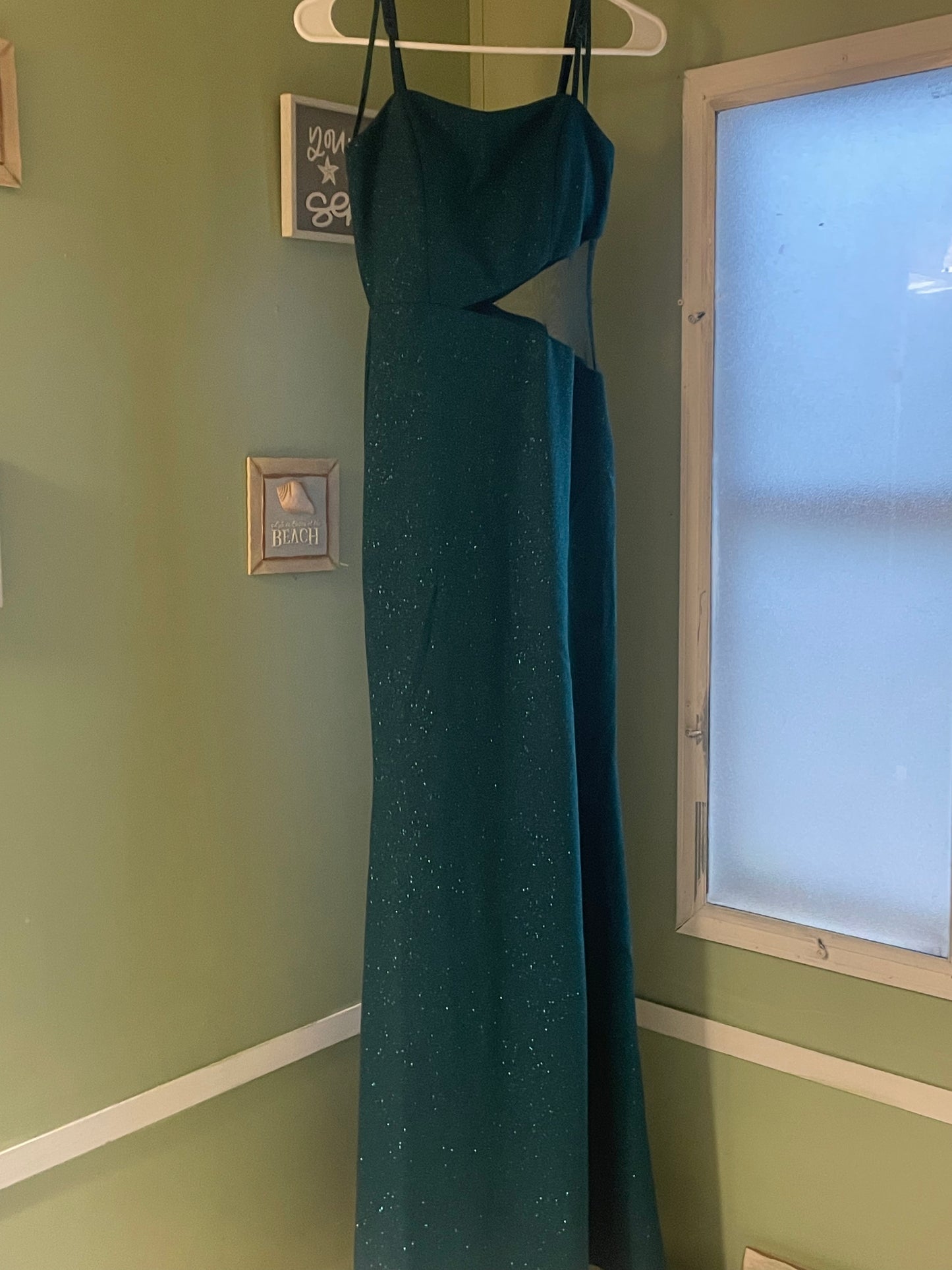 Full view of the elegant green dress hanging elegantly, showing the stunning sequin design and silhouette.