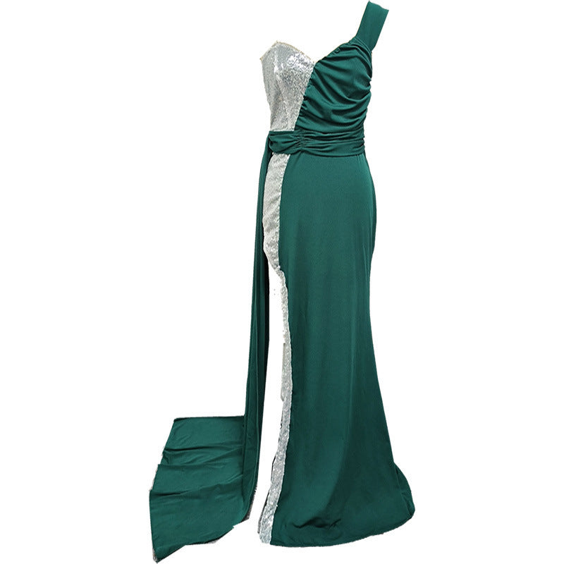 Side view of an elegant evening dress in deep green, showcasing intricate details and a long flowing train.